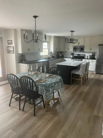 a kitchen with kitchen island a dining table chairs cabinets and wooden floor
