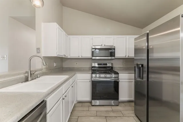 a kitchen with stainless steel appliances granite countertop a refrigerator and a stove top oven