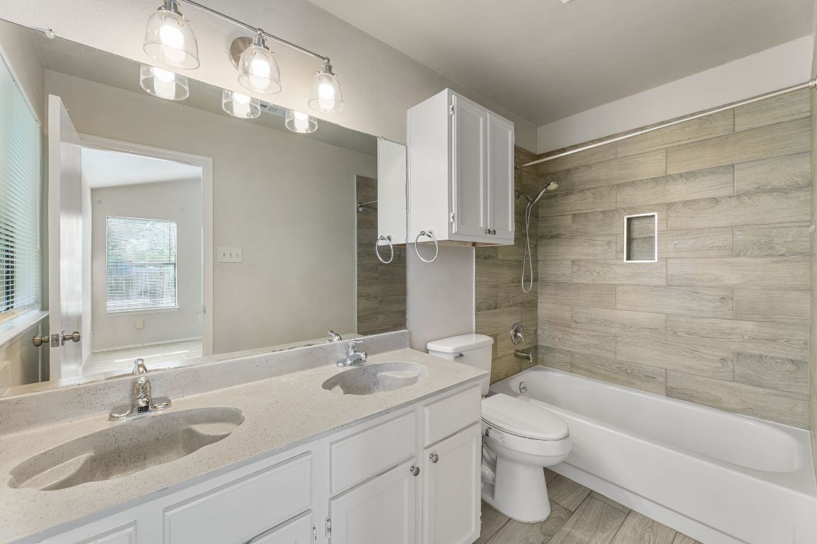 1808 Prairie Star Lane Round Rock, TX 78664 - Photo 23 of 32 a bathroom with a toilet a sink a mirror a bathtub and vanity