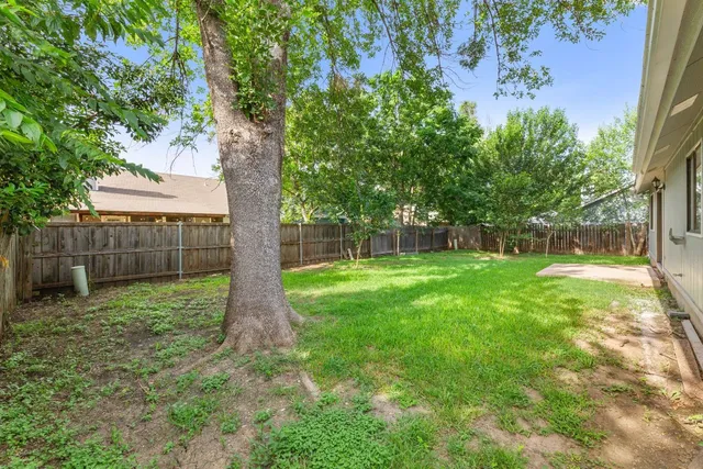 a view of a house with a yard and a large tree