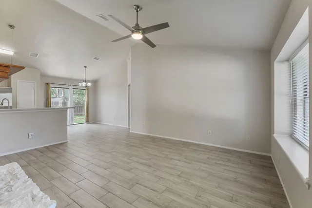 an empty room with wooden floor fan and windows