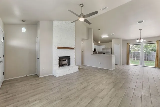 a view of a livingroom with a fireplace a ceiling fan and windows