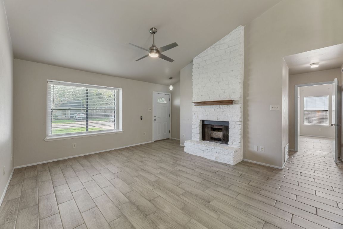 1808 Prairie Star Lane Round Rock, TX 78664 - Photo 10 of 32 an empty room with windows a fireplace a ceiling fan and wooden floor