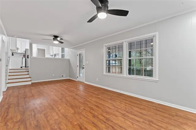 a view of a room with wooden floor and a ceiling fan
