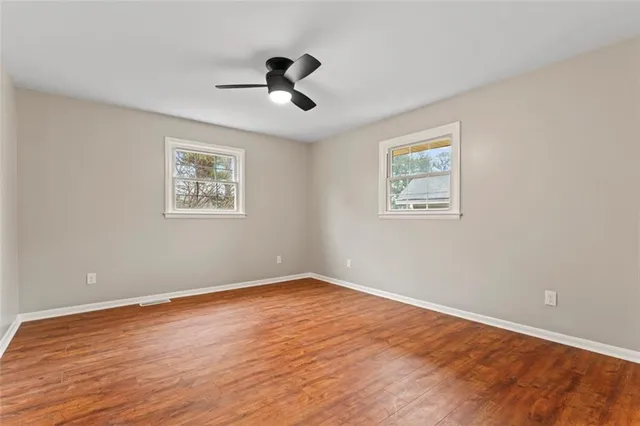 a view of empty room with wooden floor and windows