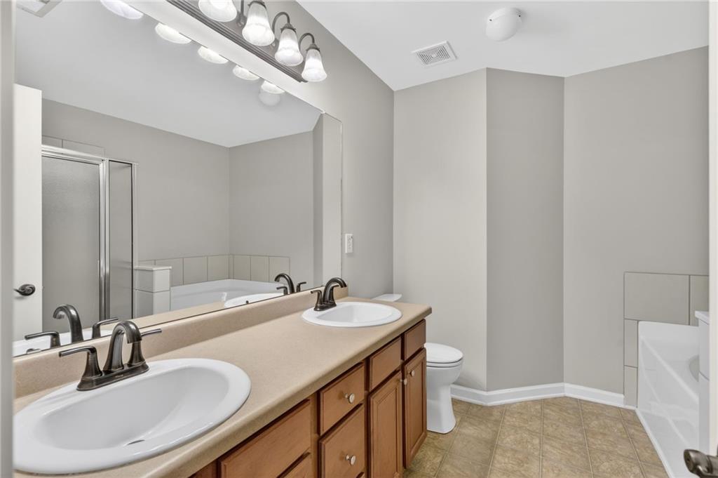 1186 Lake Point Way Suwanee, GA 30024 - Photo 23 of 35 a bathroom with a sink a toilet and a mirror