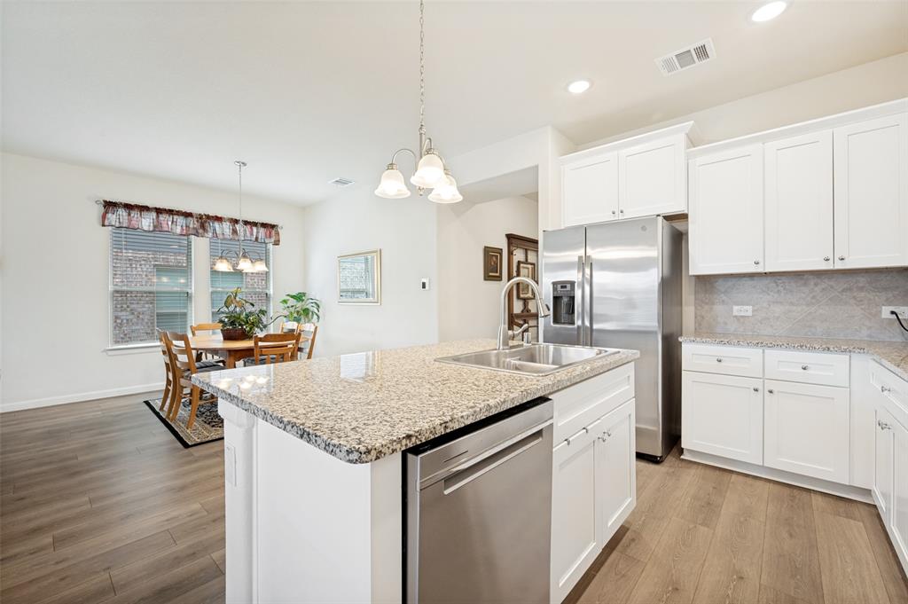 413 Wiggins Way Van Alstyne, TX 75495 - Photo 4 of 25 Kitchen island featuring a double-basin stainless steel sink with a high-arc faucet, granite countertop, and integrated dishwasher
