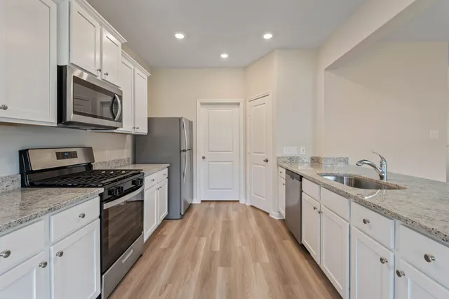 a kitchen with stainless steel appliances granite countertop a stove a sink and a refrigerator