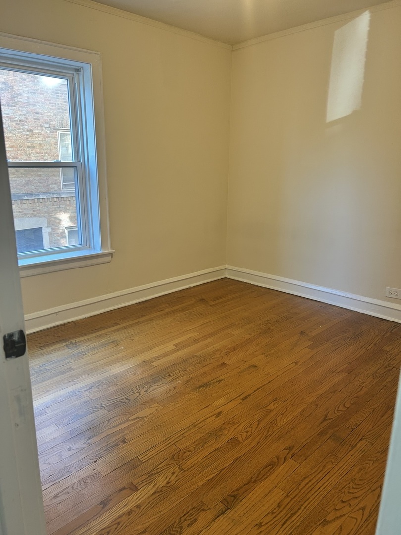 5427 West Montrose Avenue, Unit 1 Chicago, IL 60641 - Photo 8 of 13 a view of an empty room with wooden floor and a window