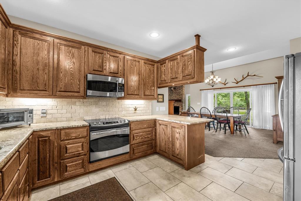 613 Bone Road Valley Mills, TX 76689 - Photo 10 of 40 a kitchen with stainless steel appliances granite countertop a stove top oven a sink dishwasher a dining table and chairs with wooden cabinets