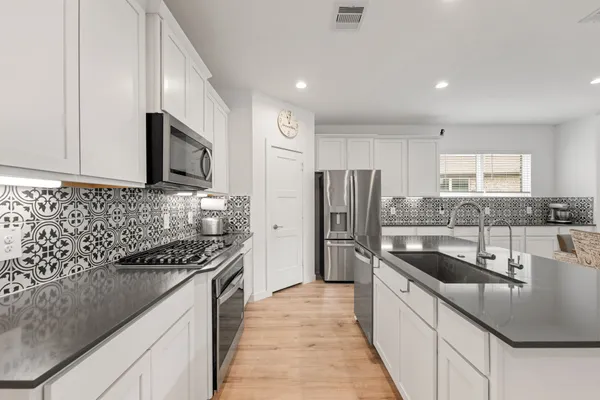a kitchen with stainless steel appliances granite countertop a sink stove and refrigerator