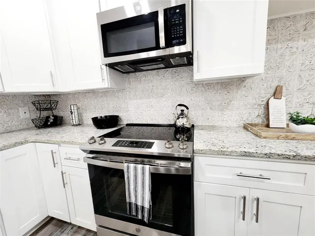 a kitchen with stainless steel appliances granite countertop white cabinets stove a sink and dishwasher