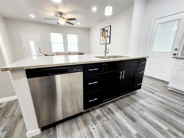 a kitchen with granite countertop a sink cabinets and wooden floor