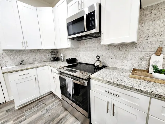 a kitchen with stainless steel appliances granite countertop a sink a stove and microwave
