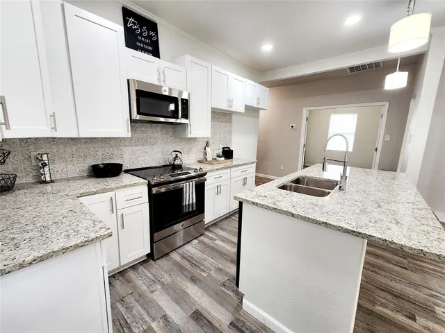 a kitchen with granite countertop white cabinets sink and stainless steel appliances
