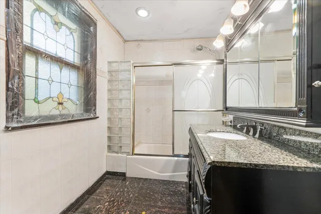 a bathroom with a granite countertop sink a mirror and a shower