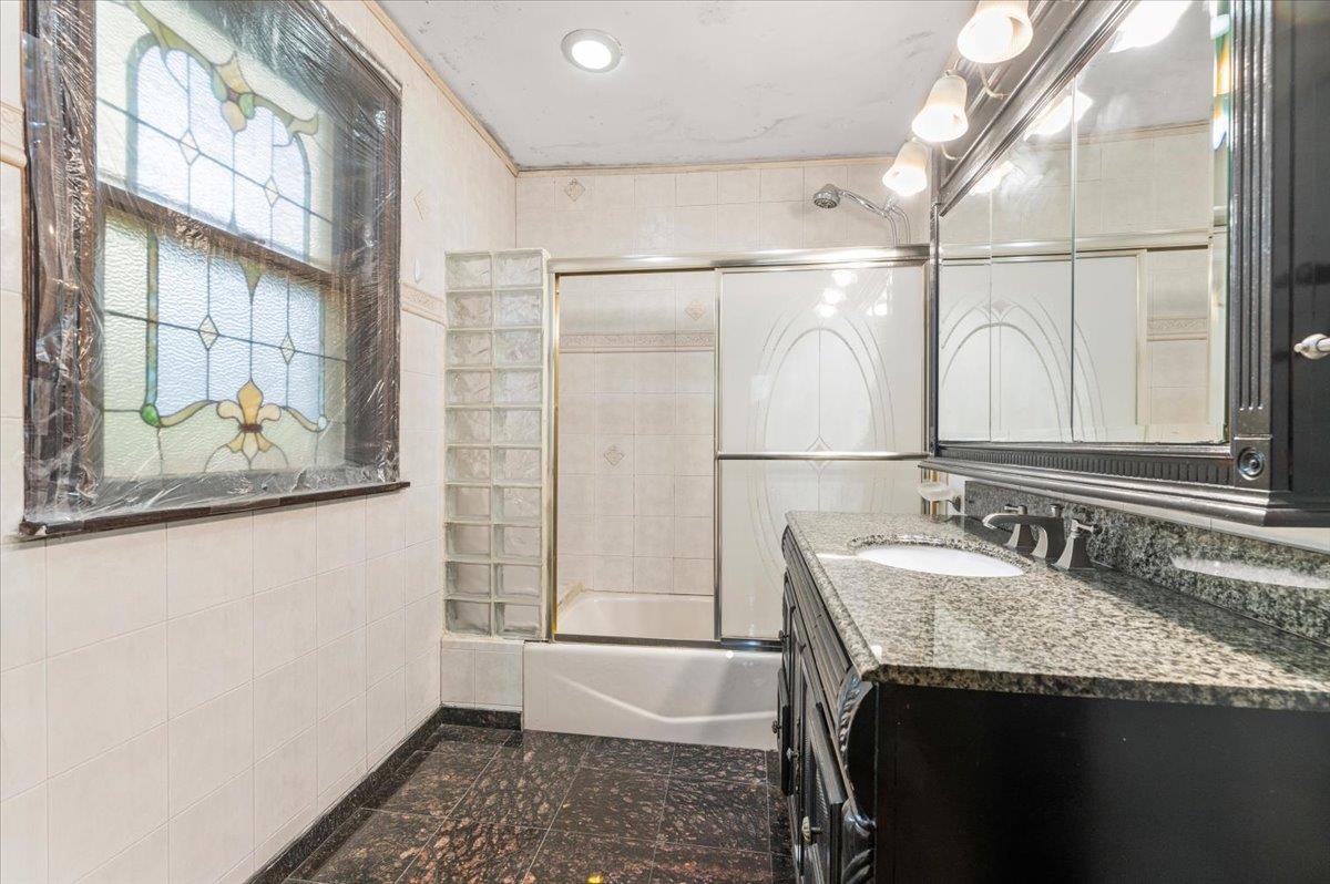 345 Broadway Lawrence, NY 11559 - Photo 17 of 25 a bathroom with a granite countertop sink a mirror and a shower
