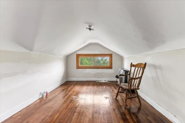 a workspace room with wooden floor lounge chair and windows