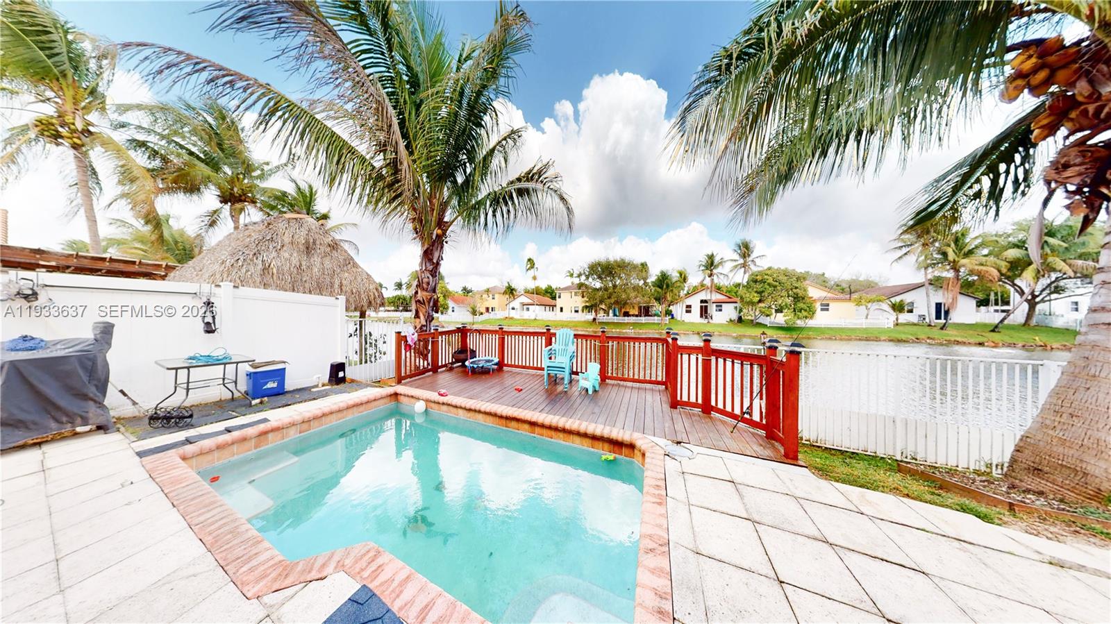 13877 Southwest 50th Street Miramar, FL 33027 - Photo 51 of 54 a view of a swimming pool with a lawn chairs under palm trees