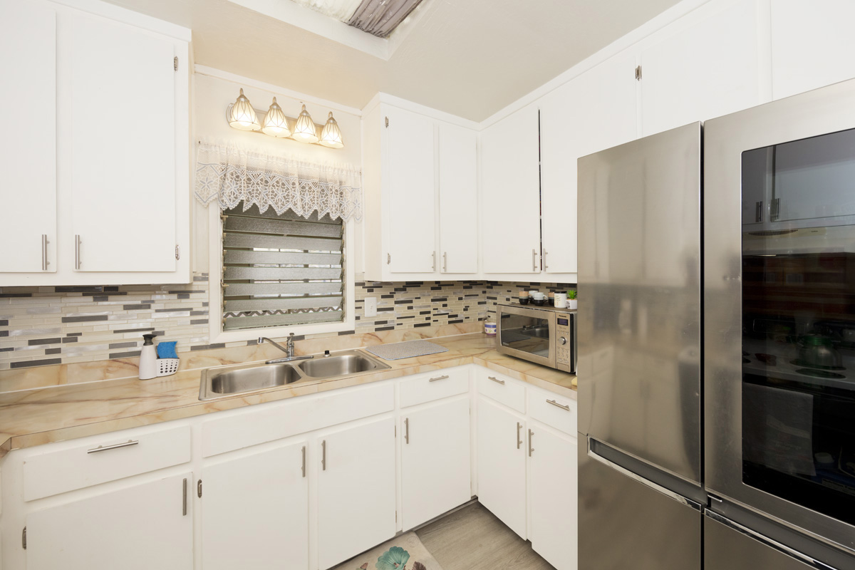 92-1663 Keaka Parkway Ocean View, HI 96704 - Photo 15 of 30 a kitchen with a refrigerator sink and cabinets