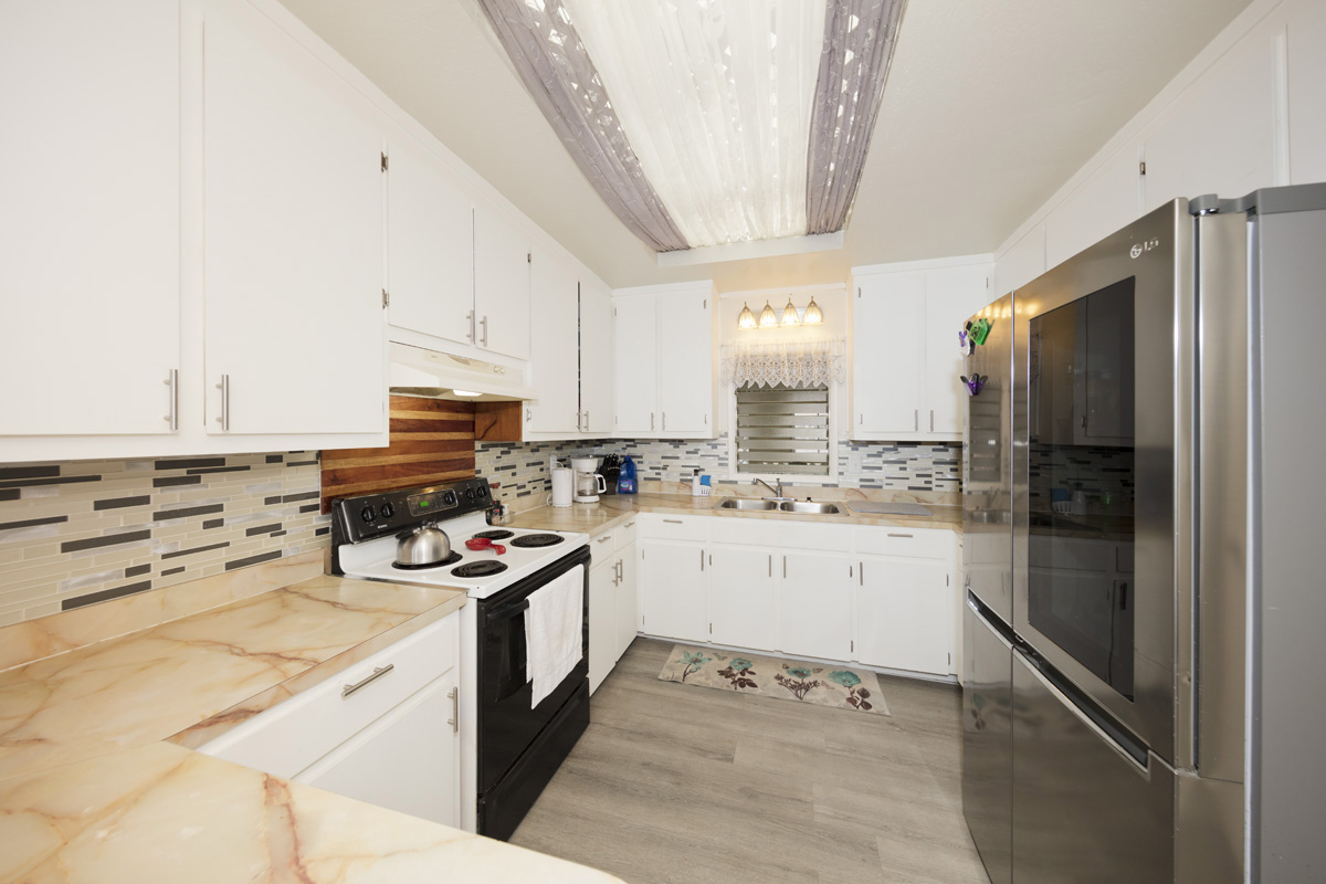 92-1663 Keaka Parkway Ocean View, HI 96704 - Photo 16 of 30 a kitchen with a refrigerator a stove a sink dishwasher and a oven with wooden floor