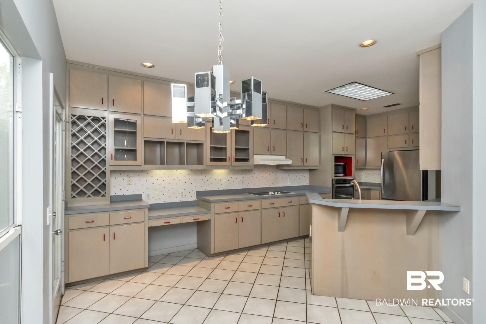 1205 Hillcrest Crossing East Mobile, AL 36695 - Photo 15 of 40 Kitchen featuring a kitchen bar, appliances with stainless steel finishes, tasteful backsplash, kitchen peninsula, and light tile patterned floors