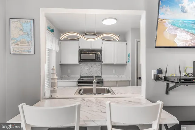 a kitchen with stainless steel appliances a stove a sink and white cabinets with wooden floor