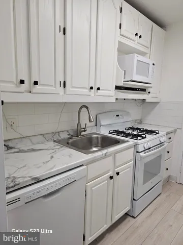 a kitchen with white cabinets and white appliances