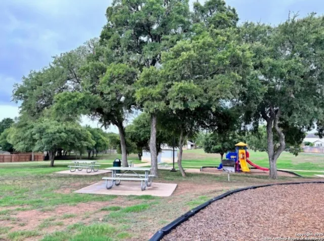 a childrens park with lots of trees and slides