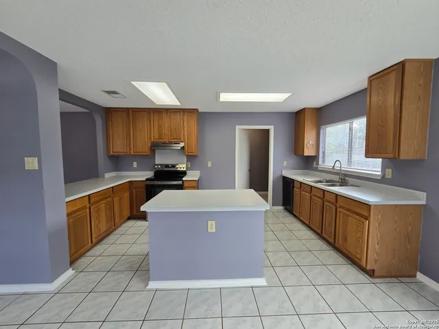 a kitchen with stainless steel appliances a stove a sink a refrigerator counter space and cabinets