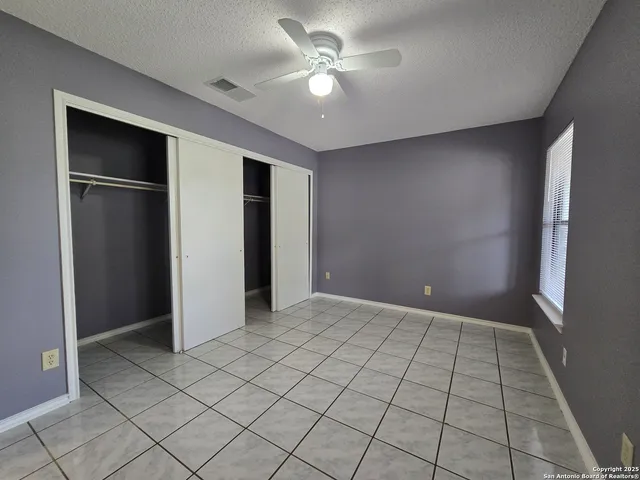 an empty room with closet and a ceiling fan
