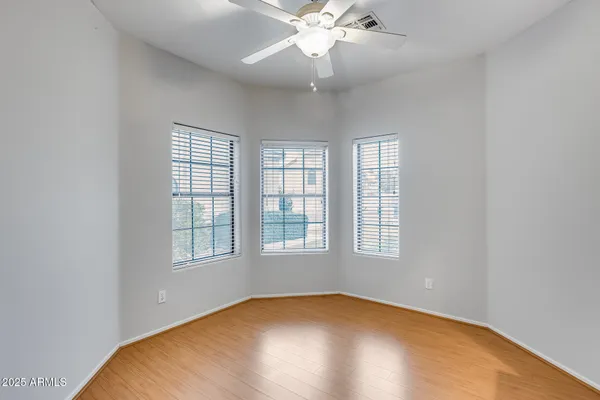 an empty room with wooden floor fan and windows