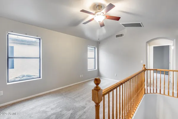 an empty room with windows and ceiling fan