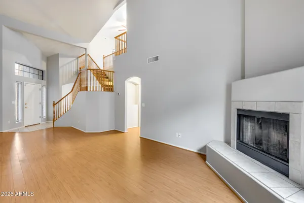 a view of an empty room with wooden floor fireplace and a window