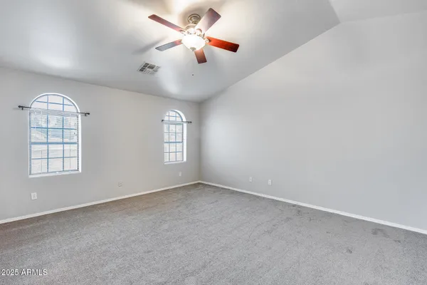 an empty room with windows and fan