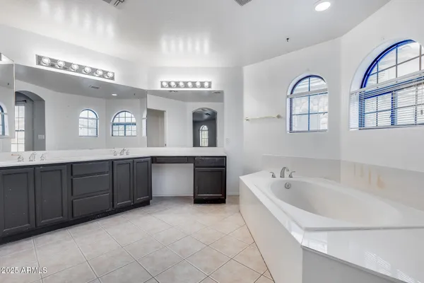 a spacious bathroom with a tub sink and mirror