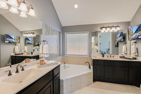 a bathroom with a sink double vanity granite tub and a mirror