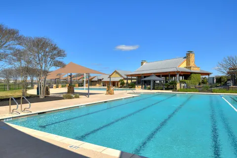 a view of a swimming pool with lawn chairs under an umbrella