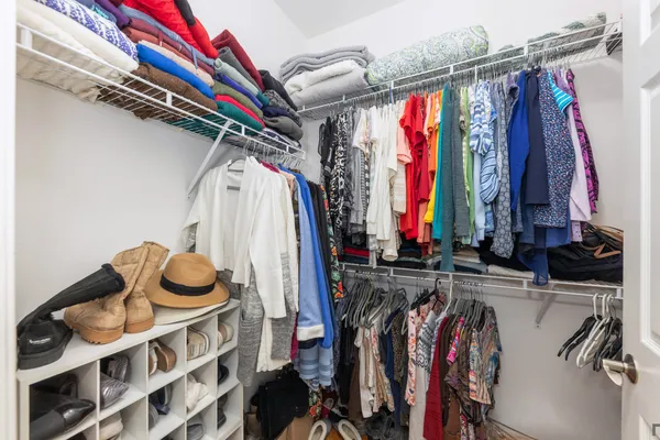 a view of walk in closet with clothes and shoes