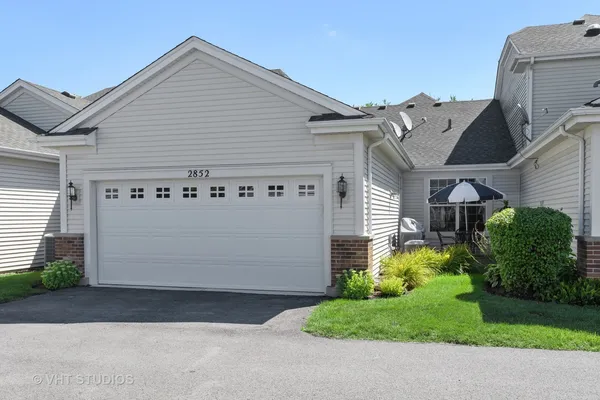 a view of a white house with a small yard and a garage