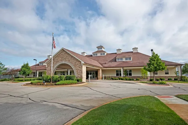 a front view of a building with lots of cars and trees