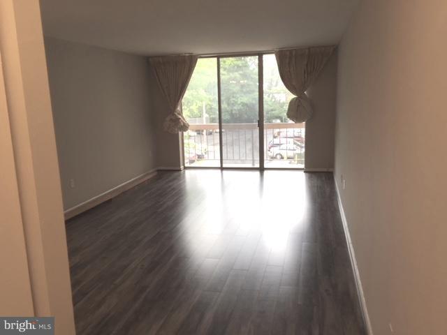 130 Slade Avenue, Unit 302 Baltimore, MD 21208 - Photo 5 of 5 an empty room with wooden floor and glass door