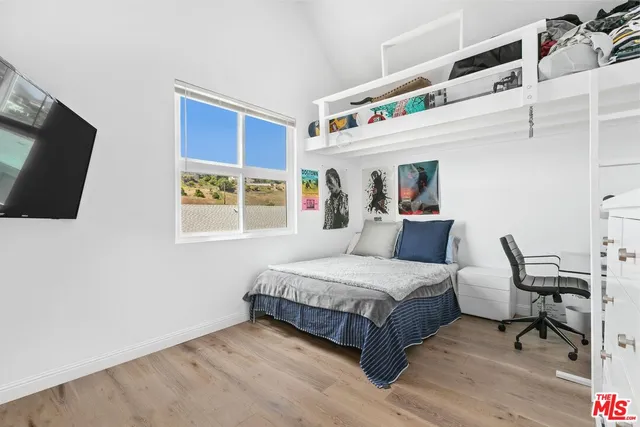 a bedroom with a bed a flat screen tv and a window