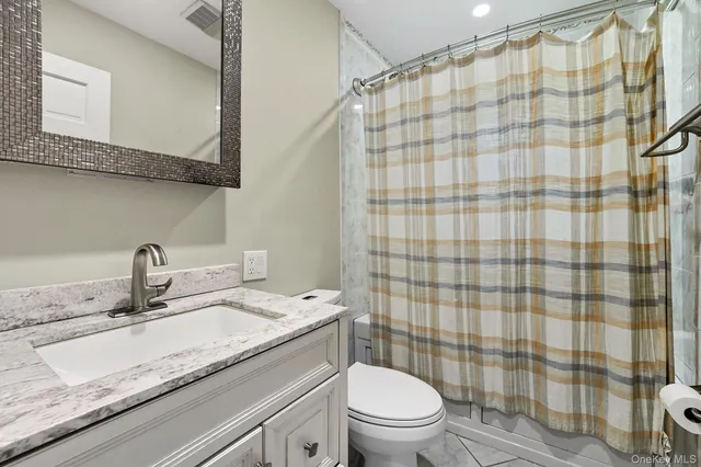 a bathroom with a granite countertop sink a toilet and shower curtain