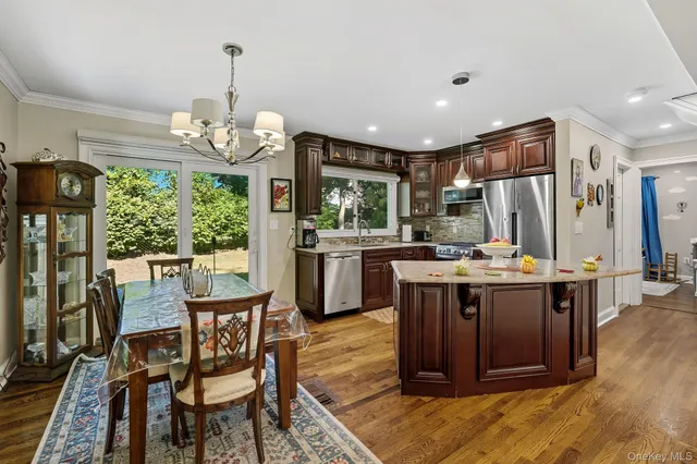 a kitchen with stainless steel appliances granite countertop wooden floors and a view of living room
