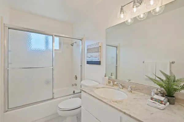 a bathroom with a granite countertop sink a toilet a mirror and shower