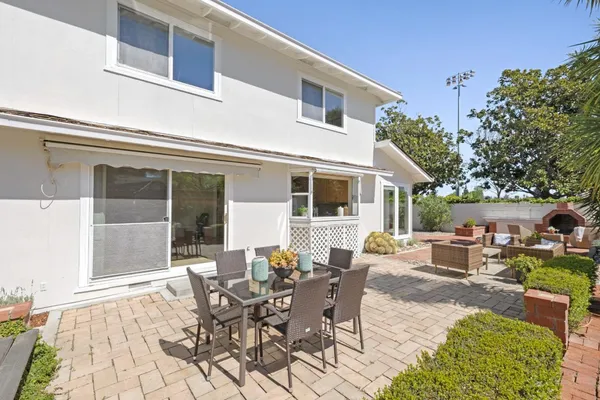 a view of a patio with table and chairs potted plants and floor to ceiling window