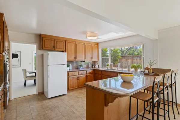 a kitchen with a table chairs refrigerator and window