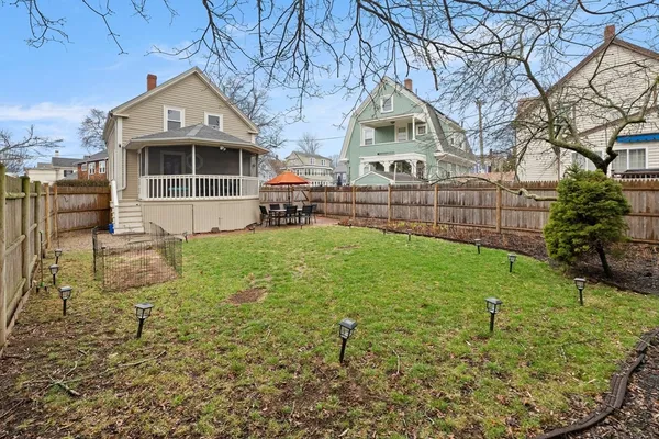 a view of backyard with seating space and wooden fence