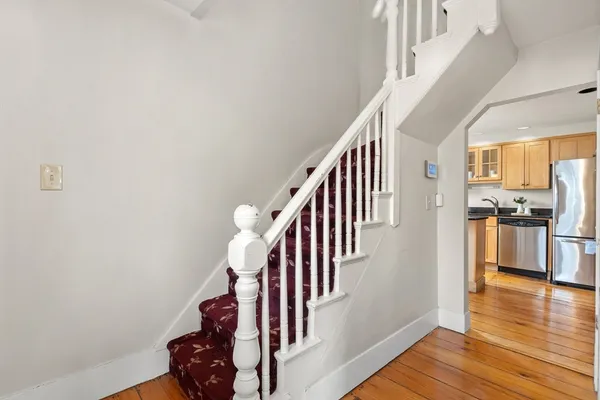 a kitchen with stainless steel appliances granite countertop a refrigerator a sink dishwasher a stove and white cabinets with wooden floor